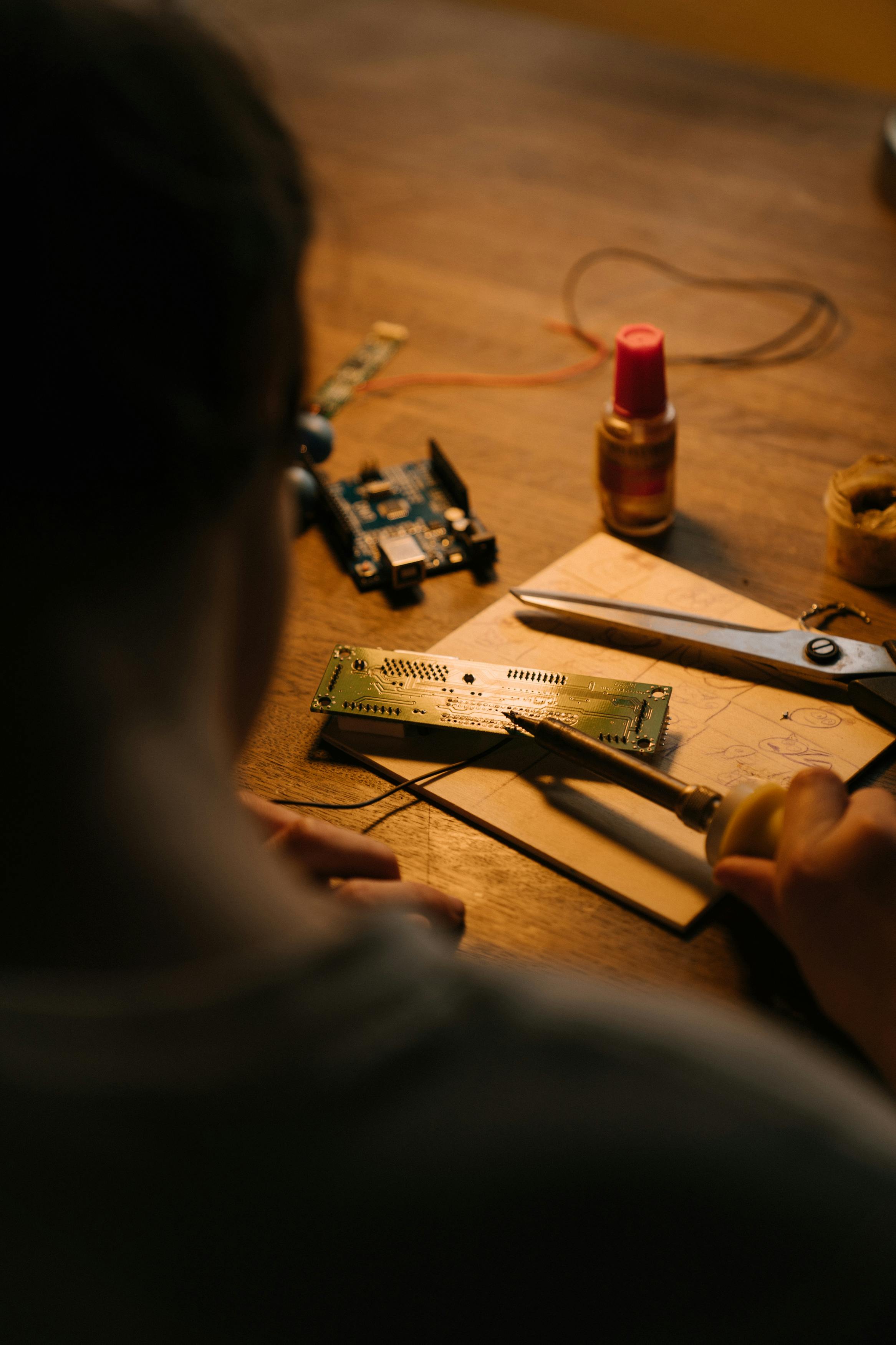 Hands soldering electronics at a workstation